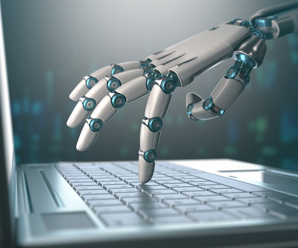 Robot hand pressing laptop keyboard keys